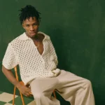 Picture of Nigerian singer Joeboy sitting on a small wooden chair.